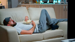 mann-liegt-auf-dem-sofa-isst-popcron-und-sieht-fern.jpg